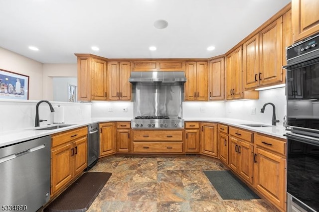 kitchen featuring under cabinet range hood, appliances with stainless steel finishes, light countertops, and a sink