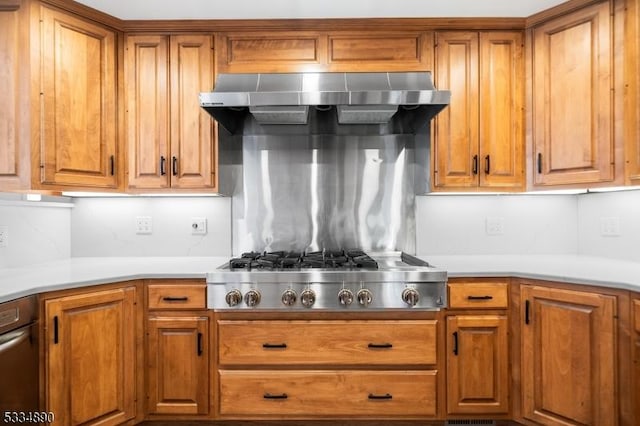 kitchen featuring wall chimney exhaust hood, stainless steel gas cooktop, brown cabinets, and light countertops