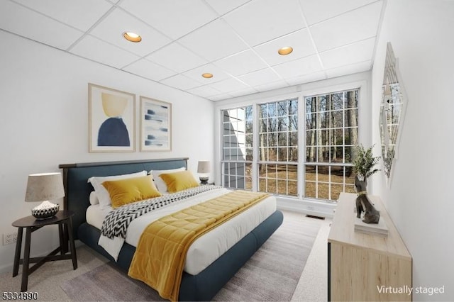 carpeted bedroom with a paneled ceiling, visible vents, and recessed lighting