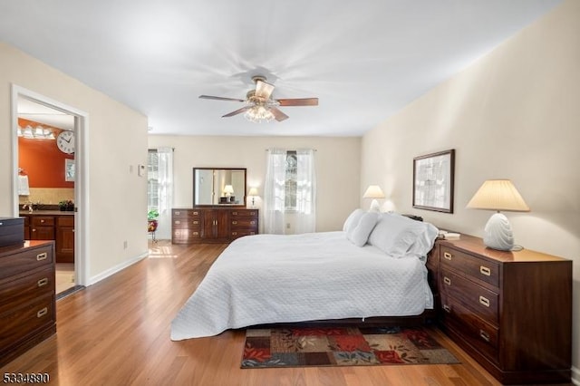 bedroom with a ceiling fan, baseboards, wood finished floors, and ensuite bathroom