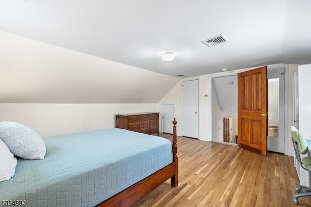 bedroom with vaulted ceiling, visible vents, and light wood-style floors