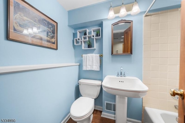 bathroom featuring washtub / shower combination, baseboards, a sink, and toilet