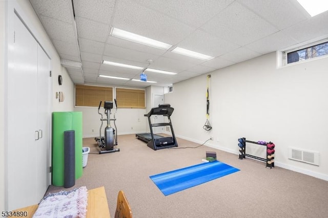 exercise room with a paneled ceiling, visible vents, and baseboards