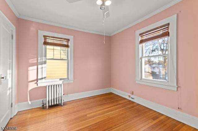 unfurnished room with ornamental molding, radiator, ceiling fan, and light wood-type flooring