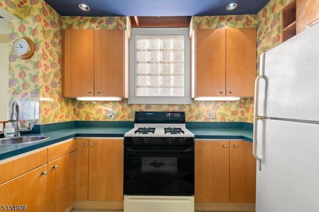 kitchen featuring white fridge, sink, and gas range oven