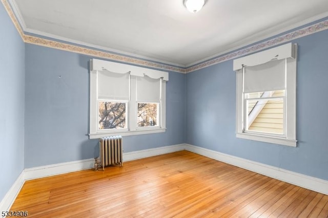 spare room featuring radiator, crown molding, and hardwood / wood-style floors