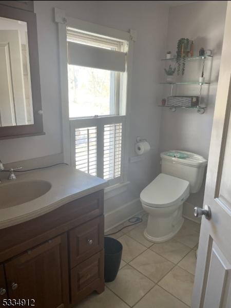 bathroom with baseboards, vanity, toilet, and tile patterned floors