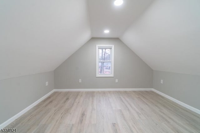 additional living space with vaulted ceiling and light hardwood / wood-style flooring