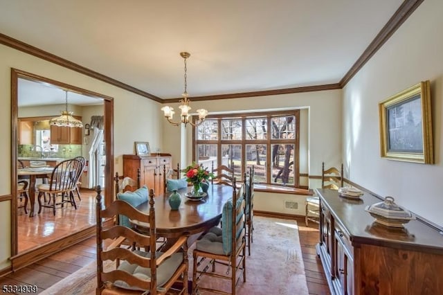 dining room with crown molding, wood-type flooring, and an inviting chandelier