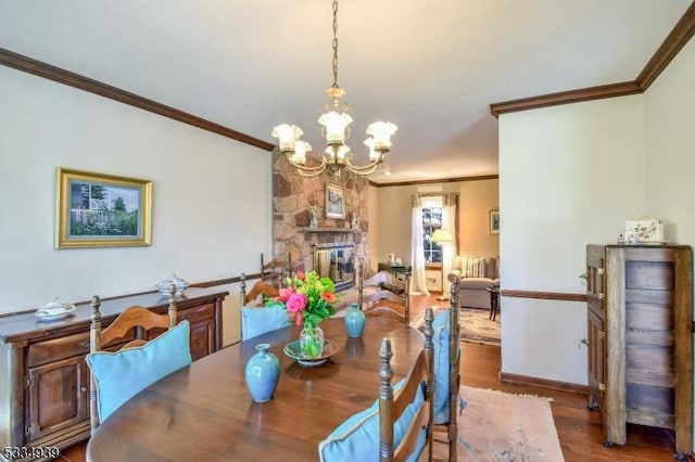 dining area with hardwood / wood-style floors, crown molding, a fireplace, and a chandelier