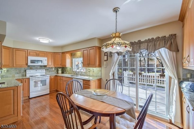 kitchen with sink, white appliances, light stone countertops, light hardwood / wood-style floors, and decorative backsplash