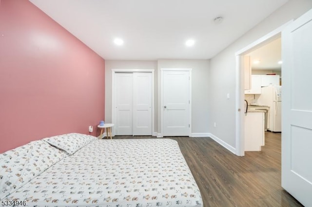 bedroom with dark wood-type flooring, a closet, and white fridge