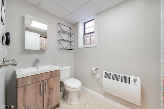 bathroom featuring vanity, heating unit, a drop ceiling, tile patterned floors, and toilet