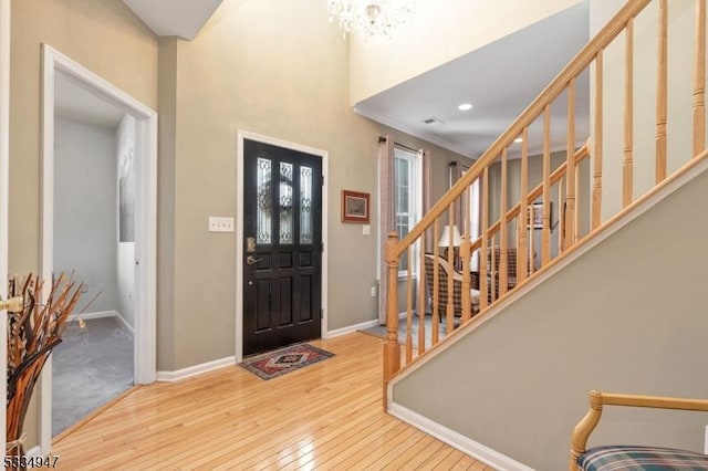 foyer entrance with a notable chandelier, wood-type flooring, and a high ceiling