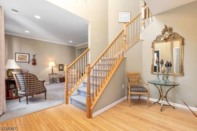 staircase with wood-type flooring and ornamental molding