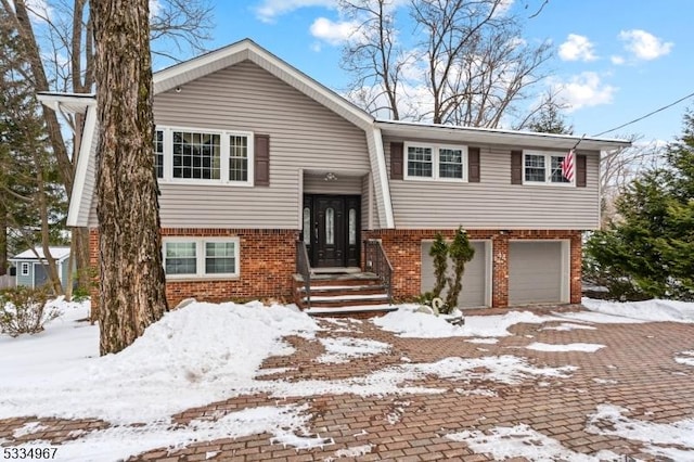 raised ranch featuring a garage and brick siding