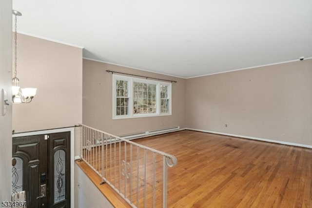 foyer entrance with baseboards, a baseboard radiator, ornamental molding, wood finished floors, and an inviting chandelier