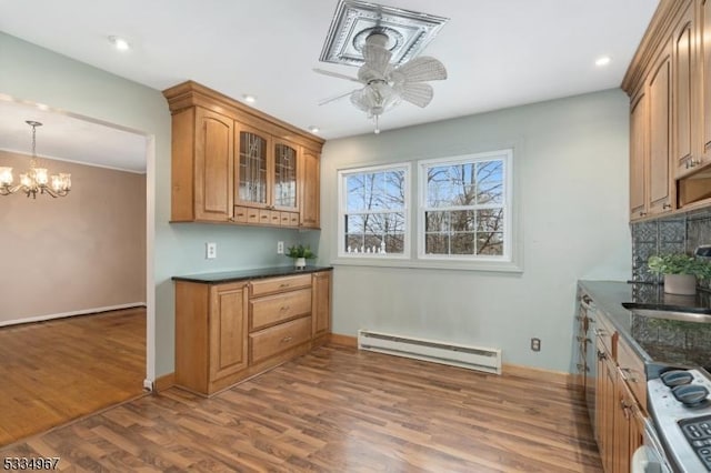 kitchen featuring gas range, a baseboard radiator, glass insert cabinets, wood finished floors, and ceiling fan with notable chandelier