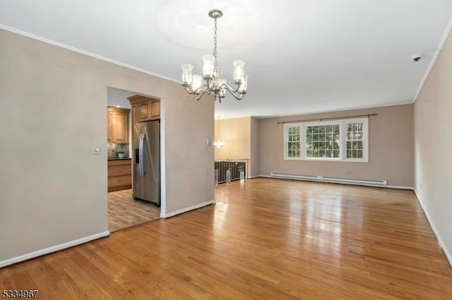 empty room featuring a baseboard heating unit, light wood finished floors, ornamental molding, and an inviting chandelier