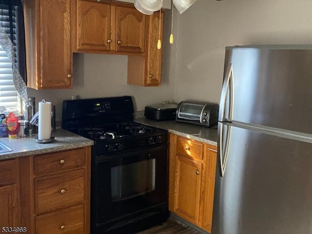 kitchen with black gas range oven and stainless steel refrigerator