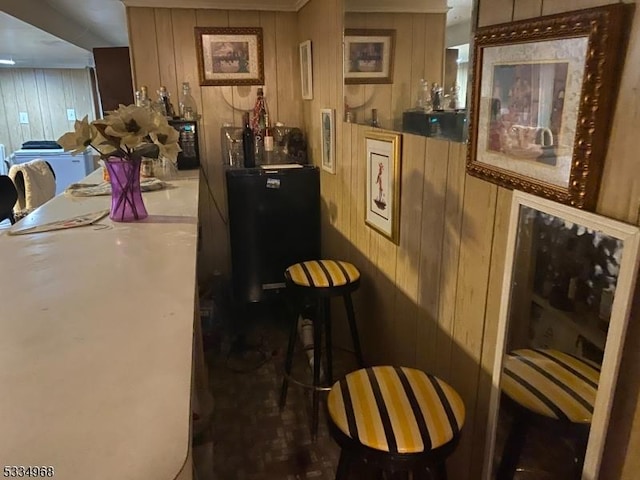 bar with black refrigerator and wooden walls