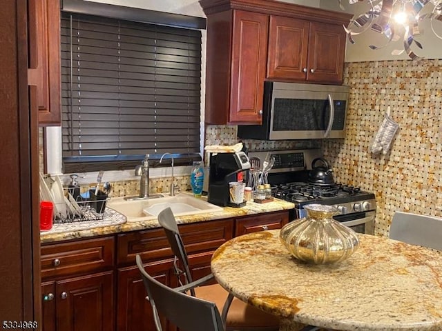 kitchen featuring light stone counters, sink, stainless steel appliances, and a breakfast bar