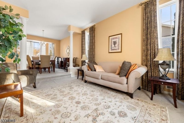 living room with ornate columns, light carpet, and a notable chandelier