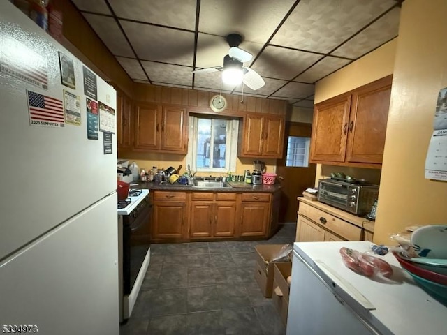 kitchen featuring ceiling fan, gas range oven, sink, and white fridge