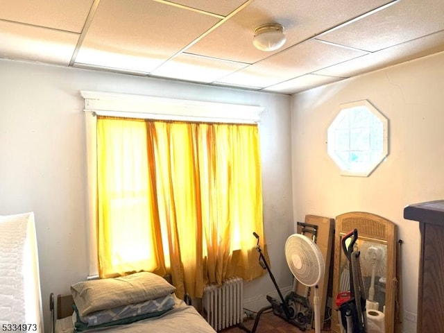 bedroom with radiator heating unit and a paneled ceiling