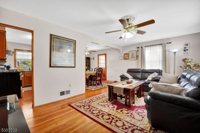 living room featuring a wealth of natural light, ceiling fan, and light hardwood / wood-style flooring