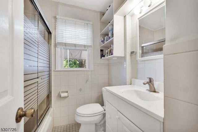 full bathroom featuring toilet, combined bath / shower with glass door, tile walls, vanity, and tile patterned flooring