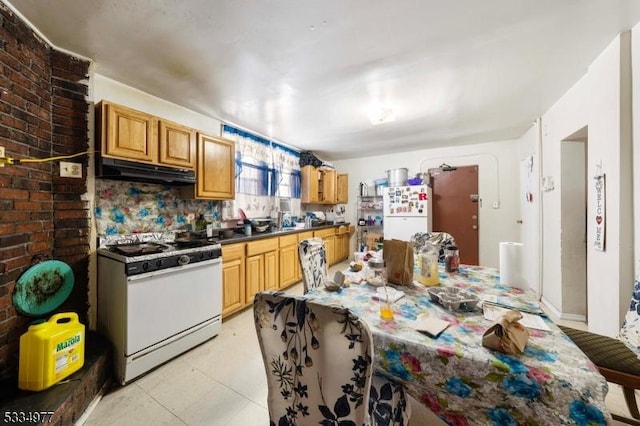 kitchen with brick wall, light tile patterned floors, and white appliances