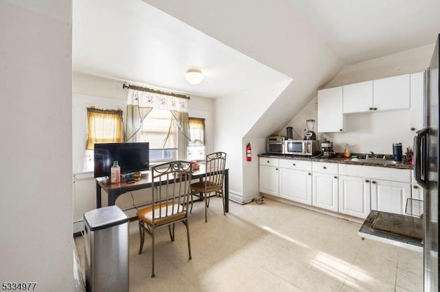 kitchen featuring lofted ceiling, sink, baseboard heating, white cabinetry, and stainless steel appliances