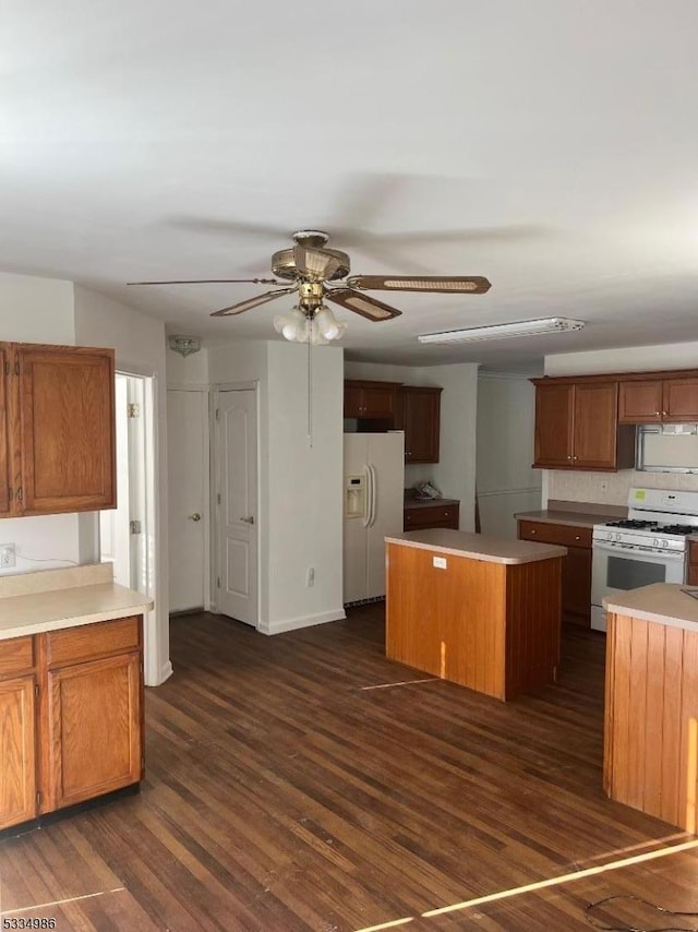 kitchen featuring dark wood-type flooring, tasteful backsplash, a center island, ceiling fan, and white appliances