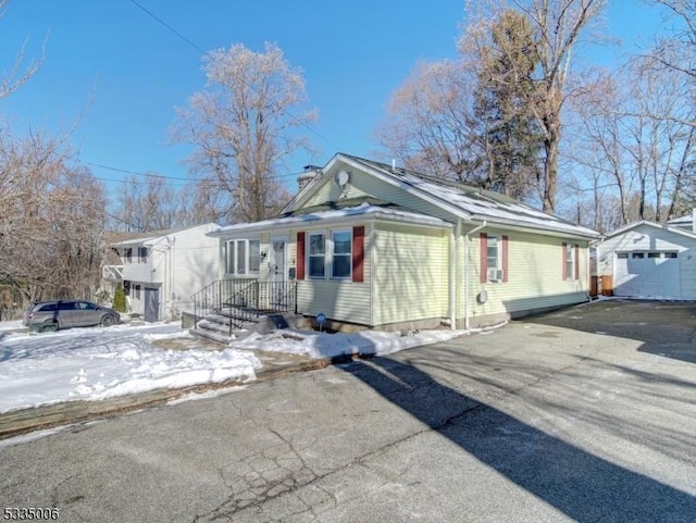 snow covered property with a garage and an outdoor structure