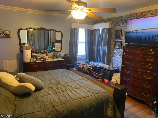 bedroom with wood-type flooring, ornamental molding, and ceiling fan