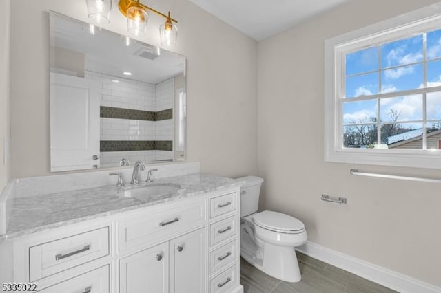 bathroom with vanity, hardwood / wood-style flooring, toilet, and tiled shower