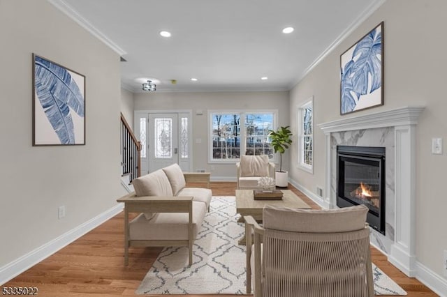 living room featuring crown molding, a fireplace, and light hardwood / wood-style floors