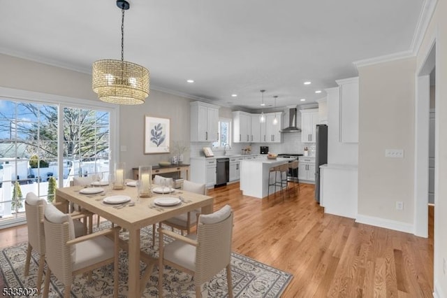 dining room featuring crown molding, sink, a chandelier, and light hardwood / wood-style floors