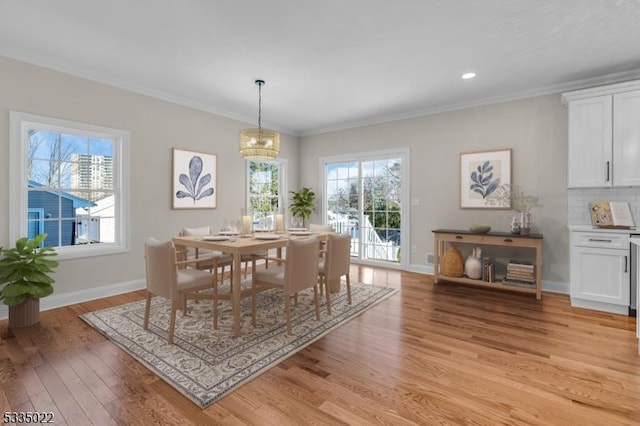 dining space featuring ornamental molding, a healthy amount of sunlight, a chandelier, and light hardwood / wood-style flooring