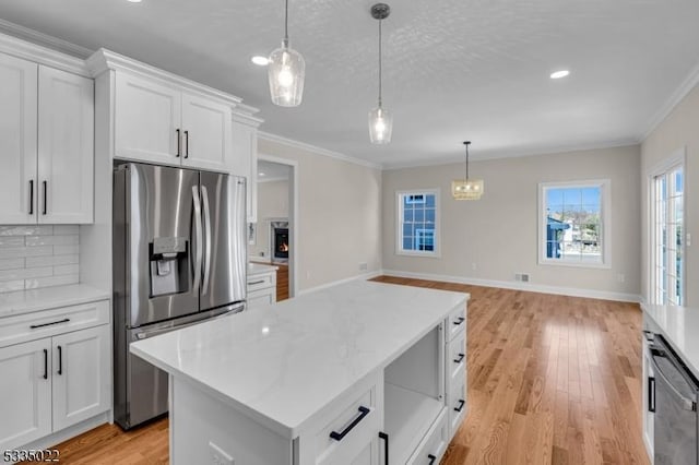 kitchen with appliances with stainless steel finishes, light wood-type flooring, hanging light fixtures, and white cabinets