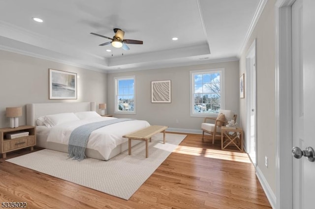 bedroom with hardwood / wood-style flooring, ceiling fan, ornamental molding, and a raised ceiling