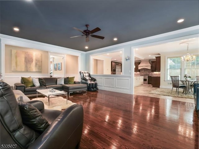 living room with crown molding, ceiling fan with notable chandelier, and hardwood / wood-style floors