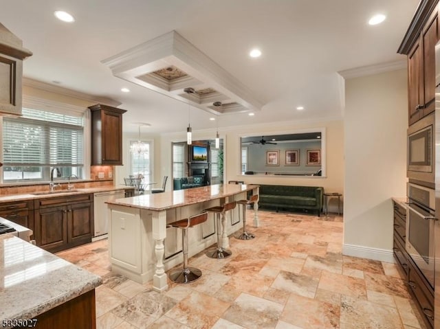 kitchen with a kitchen island, appliances with stainless steel finishes, sink, a kitchen breakfast bar, and crown molding