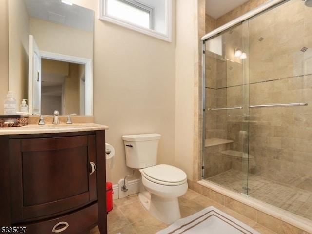 bathroom featuring vanity, toilet, a shower with shower door, and tile patterned flooring