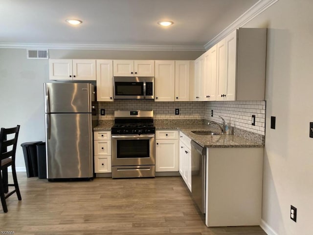 kitchen featuring appliances with stainless steel finishes, sink, dark stone countertops, and white cabinets