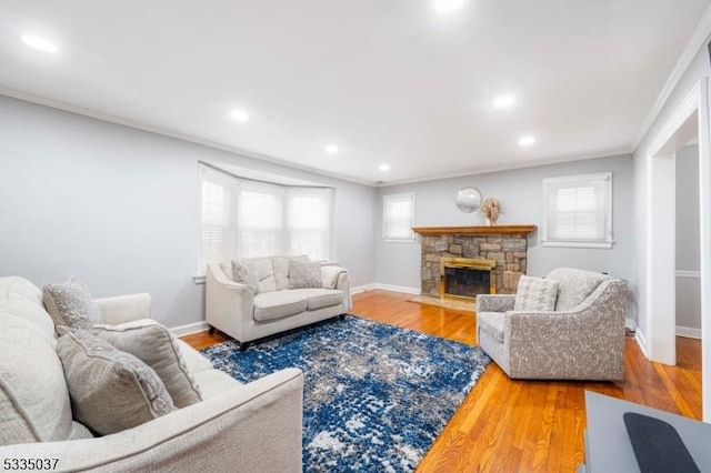 living room featuring crown molding, a stone fireplace, and hardwood / wood-style floors