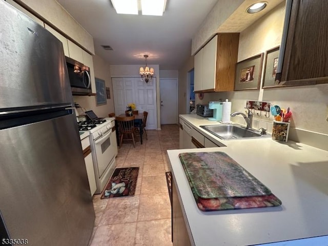 kitchen featuring sink, light tile patterned floors, stainless steel appliances, decorative light fixtures, and a chandelier