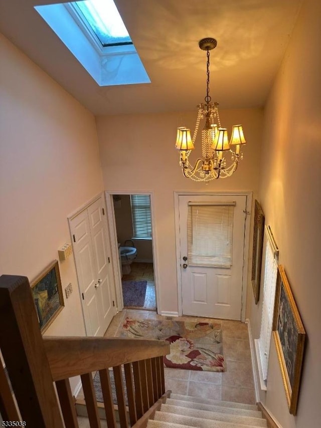 foyer featuring a notable chandelier, light tile patterned floors, a skylight, and a high ceiling