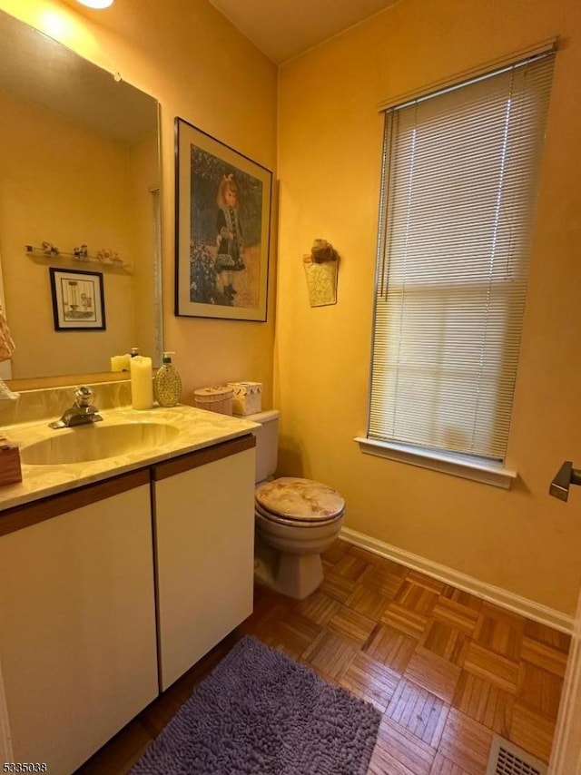 bathroom with vanity, parquet flooring, and toilet